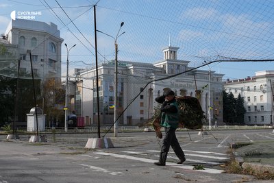 Олексій виносить з клумби обрізані засохлі трояндові кущі. Можливіть прибрати місто зʼявилась завдяки оголошеному кількаденному режиму тиші на Херсонщині для евакуації людей з окупованих Олешків. Херсон, 28 жовтня 2026 року Олексій виносить з клумби обрізані засохлі трояндові кущі. Можливіть прибрати місто зʼявилась завдяки оголошеному кількаденному режиму тиші на Херсонщині для евакуації людей з окупованих Олешків. Херсон, 28 жовтня 2026 року