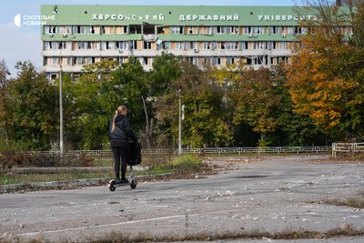 Жінка проїжджає на самокаті повз зруйнований російськими обстрілами корпус Херсонського державного університету, 28 жовтня 2026 року Жінка проїжджає на самокаті повз зруйнований російськими обстрілами корпус Херсонського державного університету, 28 жовтня 2026 року