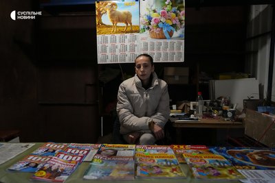 Продавчиня у кіоску з пресою Юлія сидить під друкованими календарями на наступний 2027 рік. Жінка каже, що людей на ринку у дні режиму тиші значно побільшало. Херсон, 28 жовтня 2026 року Продавчиня у кіоску з пресою Юлія сидить під друкованими календарями на наступний 2027 рік. Жінка каже, що людей на ринку у дні режиму тиші значно побільшало. Херсон, 28 жовтня 2026 року