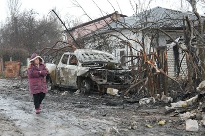 Жінка йде вулицею, в яку влучили російські дрони Жінка йде вулицею, в яку влучили російські дрони