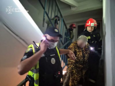 Рятувальник і поліцейський виводять жінку на вулицю Рятувальник і поліцейський виводять жінку на вулицю