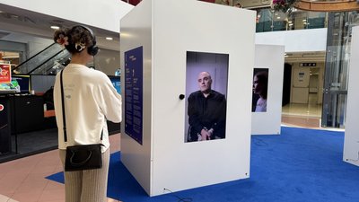 Відвідувачка виставки "Поговори зі мною" слухає історію чоловіка, який виховувався в інтернаті Відвідувачка виставки "Поговори зі мною" слухає історію чоловіка, який виховувався в інтернаті