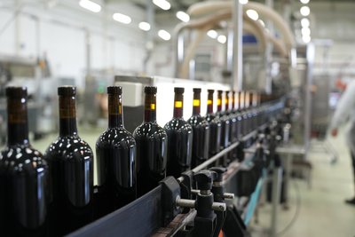 Процес розлиття вина по пляшках на виноробні Процес розлиття вина по пляшках на виноробні