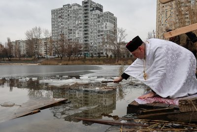 Священник освячує воду в Йорданському озері на Оболоні у Києві на Водохреще Священник освячує воду в Йорданському озері на Оболоні у Києві на Водохреще
