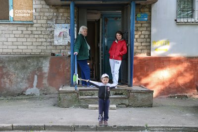 Мешканці будинку в Центральному районі Херсона стоять біля входу в підʼїзд та до укриття, яке облаштоване у підвалі