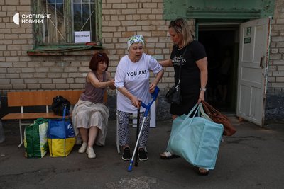 Жінки біля точки реєстрації місцевих жителів, яких волонтери щойно вивезли з Острова. Місцевих жителів закликали виїжджати після того, як російська армія 2 серпня вдарила з авіації по автомобільному мосту. Херсон, 4 серпня 2025 року