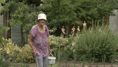 Жінка вирощує квіти та городину Жінка вирощує квіти та городину