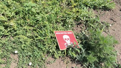 Табличка із застереженням про небезпеку, яка лишилась на полі після розмінування