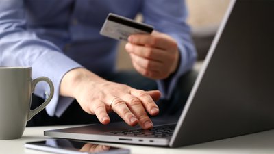 Людина тримає у руках банківську картку Людина тримає у руках банківську картку
