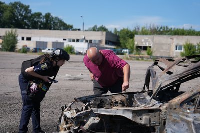 Оглядає згорілу машину поліція і власник після влучання у Харкові Оглядає згорілу машину поліція і власник після влучання у Харкові