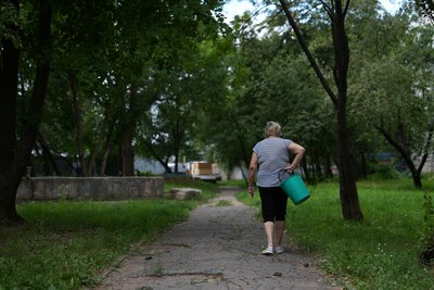Жінка йде з відром по вулиці Жінка йде з відром по вулиці
