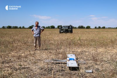 Працівник фермерського господарства дивититься на російський ударний дрон "Молнія-1", який приземлився в полі напередодні. Херсонщина, липень 2025 року