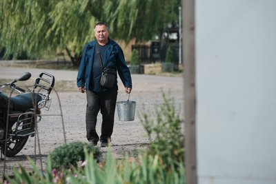 Чоловік йде з відром вулицею села Чоловік йде з відром вулицею села