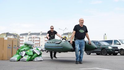 Чоловіки несуть човен, щоб завантажити його в авто, яке поїде рятувати людей від водопілля на Херсонщині