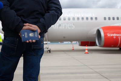 Чоловік тримає українські паспорти, чекаючи на злітній смузі поруч із літаком медичної евакуації в аеропорту Кельн-Бонн у Німеччині, 23 березня 2023 року Чоловік тримає українські паспорти, чекаючи на злітній смузі поруч із літаком медичної евакуації в аеропорту Кельн-Бонн у Німеччині, 23 березня 2023 року
