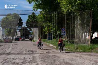 Жінки проїжджають по вулиці, накритій антидроновими сітками у Нововоронцовці на Херсонщині, травень 2026 року Жінки проїжджають по вулиці, накритій антидроновими сітками у Нововоронцовці на Херсонщині, травень 2026 року