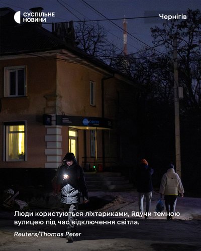 Люди користуються ліхтариками, йдучи темною вулицею під час відключення світла у Чернігові Люди користуються ліхтариками, йдучи темною вулицею під час відключення світла у Чернігові