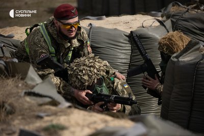 Інструктор навчального центру допомагає новобранцю прицілити рушницю під час виконання вправи із зачистки траншей від противника Інструктор навчального центру допомагає новобранцю прицілити рушницю під час виконання вправи із зачистки траншей від противника