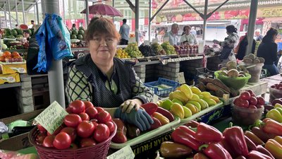 Продавчиня на ринку продає овочі