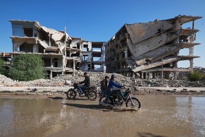Молодь на мотоциклах проїжджає через калюжу біля пошкодженої під час активних бойових дій будівлі у таборі Ярмук у Дамаску. Сирія, 7 грудня 2025 року. Цей табір побудували ще у 1957 році як прихисток для палестинських біженців Молодь на мотоциклах проїжджає через калюжу біля пошкодженої під час активних бойових дій будівлі у таборі Ярмук у Дамаску. Сирія, 7 грудня 2025 року. Цей табір побудували ще у 1957 році як прихисток для палестинських біженців