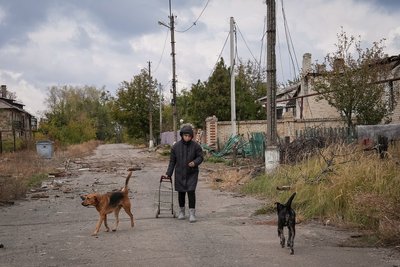 Місцева жінка йде вулицею зі своїми собаками у прифронтовому місті Часів Яр на Донеччині, 16 жовтня 2024 року Місцева жінка йде вулицею зі своїми собаками у прифронтовому місті Часів Яр на Донеччині, 16 жовтня 2024 року