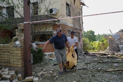 чоловіки несуть тіло загиблої через обстріл жінки у Вільхівці на Харківщині, 19 червня 2024 року