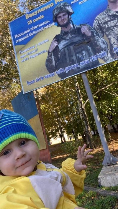 Дитина біля бігборда з військовим Максимом вакуленком Дитина біля бігборда з військовим Максимом вакуленком