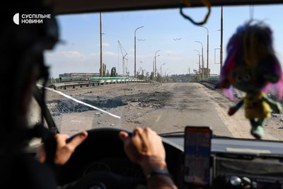 Машина евакуаційної групи ГО "Сильні Бо Вільні" проїжджає по мосту, що сполучає Острів з іншою частиною міста. На мосту — діра від удару КАБом, який росіяни скинули напередодні. Херсон, 4 серпня 2025 року