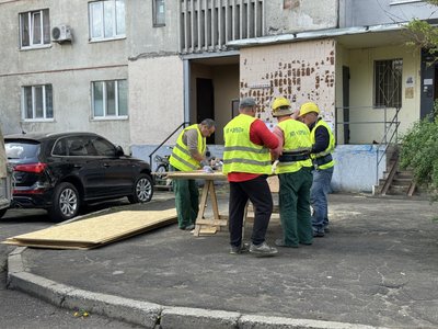 Працівники комунального підприємства допомагають забивати вікна на місці влучання у Салтівському районі Харкова Працівники комунального підприємства допомагають забивати вікна на місці влучання у Салтівському районі Харкова