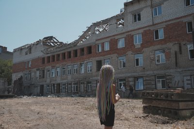 Дівчинка стоїть біля зруйнованого будинку в Харкові Дівчинка стоїть біля зруйнованого будинку в Харкові