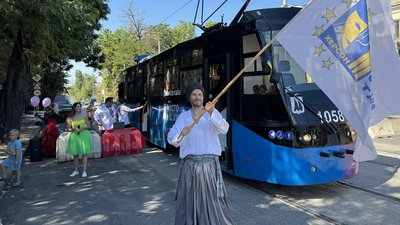 Актор тримає в руках прапор з емблемою театру Актор тримає в руках прапор з емблемою театру