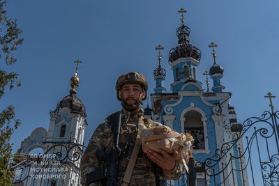 Військовий 66 окремої механізованої бригади імені князя Мстислава Хороброго тримає великодній кошик біля понівиченого обстрілами храму Військовий 66 окремої механізованої бригади імені князя Мстислава Хороброго тримає великодній кошик біля понівиченого обстрілами храму