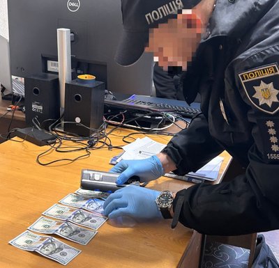 Поліцейський оглядає гроші, вилучені у підозрюваного Поліцейський оглядає гроші, вилучені у підозрюваного