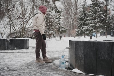 Жінка набирає воду в джерелі Жінка набирає воду в джерелі