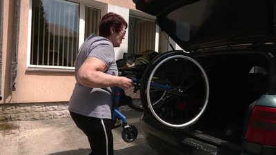 Мати Микити складає крісло колісне в машину сину Мати Микити складає крісло колісне в машину сину