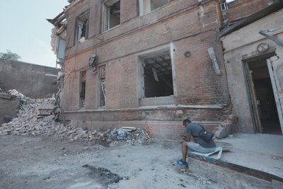 Чоловік сидить біля зруйнованого будинку в Харкові Чоловік сидить біля зруйнованого будинку в Харкові