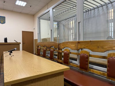 Порожня лава, де має сидіти адвокат, а також загородження зі скла для обвинуваченого Порожня лава, де має сидіти адвокат, а також загородження зі скла для обвинуваченого