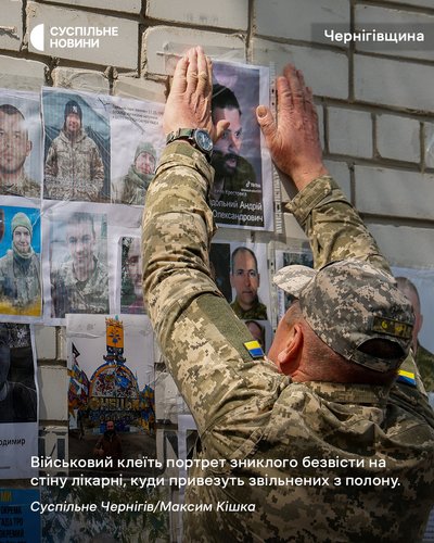 Військовий клеїть портрет зниклого безвісти на стіну лікарні, куди привезуть звільнених з полону військових на Чернігівщині, 20 червня 2025 року
