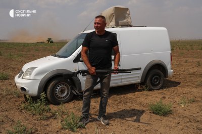 Фермер з Бериславщини Олександр Гордієнко у полі з антидроновою рушницею поряд з автівкою з РЕБом на даху. Херсонщина, липень 2025 року