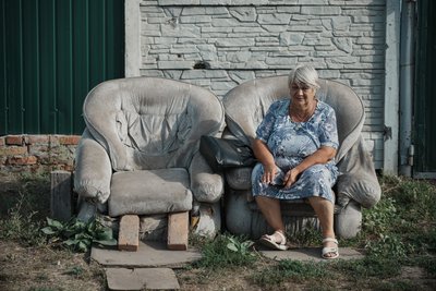 Жінка сидить на кріслі на подвір'ї Жінка сидить на кріслі на подвір'ї