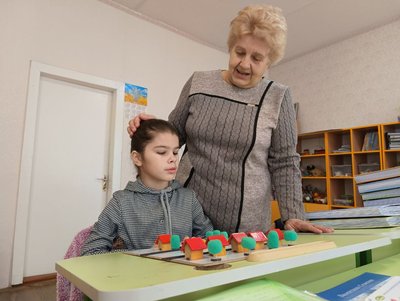 Вчителька Лідія Данильчук вивчає з Інною деревяний макет, на якому відтворений її маршрут з дому до школи Вчителька Лідія Данильчук вивчає з Інною деревяний макет, на якому відтворений її маршрут з дому до школи