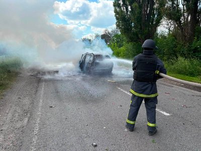 Рятувальник гасить автівку, яка зайнялася внаслідок російського удару, Богодухів, 30 червня 2026 року