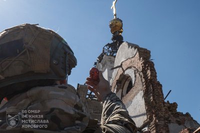 Військовий 66 окремої механізованої бригади імені князя Мстислава Хороброго тримає писанку біля понівеченого обстрілами храму Військовий 66 окремої механізованої бригади імені князя Мстислава Хороброго тримає писанку біля понівеченого обстрілами храму