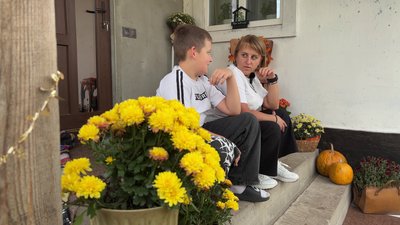 Наталія сидить на ганку із сином, поблизу із власно вирощеними квітами у горщиках Наталія сидить на ганку із сином, поблизу із власно вирощеними квітами у горщиках