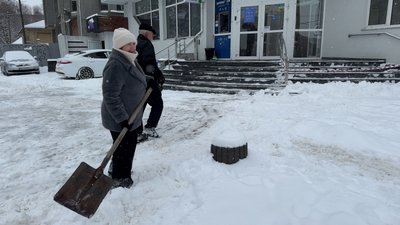 Люди розчищають сніг поблизу будівлі