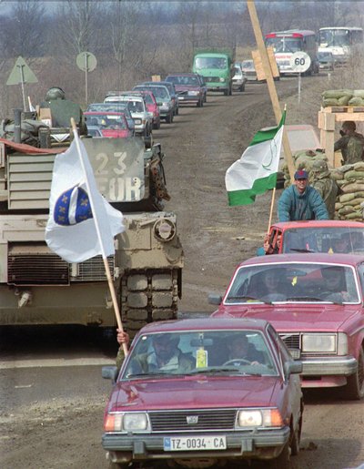 Колона автомобілів та автобусів з прапорами біля пропускного пункту, який контролюють військові НАТО, 19 березня 1996 року. П'ятсот селян-боснійців повертаються у село Мемічі за 50 на схід від Тузли. Воно було повністю зруйноване під час війни Колона автомобілів та автобусів з прапорами біля пропускного пункту, який контролюють військові НАТО, 19 березня 1996 року. П'ятсот селян-боснійців повертаються у село Мемічі за 50 на схід від Тузли. Воно було повністю зруйноване під час війни