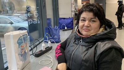 Переселенка Тетяна заряджає телефон у одному із супермаркетів міста