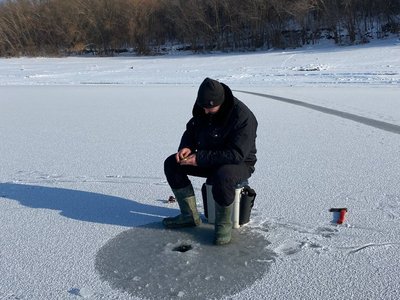 Рибалка Юрій біля лунки готується до риболовлі Рибалка Юрій біля лунки готується до риболовлі