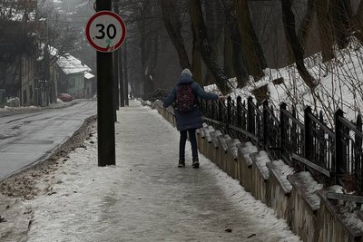 Дитина тримається за поручень огорожі, щоб не послизнутися на тротуарі у Чернівцях Дитина тримається за поручень огорожі, щоб не послизнутися на тротуарі у Чернівцях