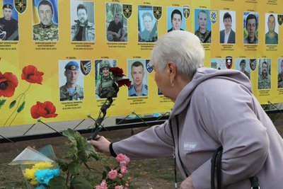 Жінка покладає квіти біля банера із загиблими воїнами на Алеї Слави у Миколаєві Жінка покладає квіти біля банера із загиблими воїнами на Алеї Слави у Миколаєві
